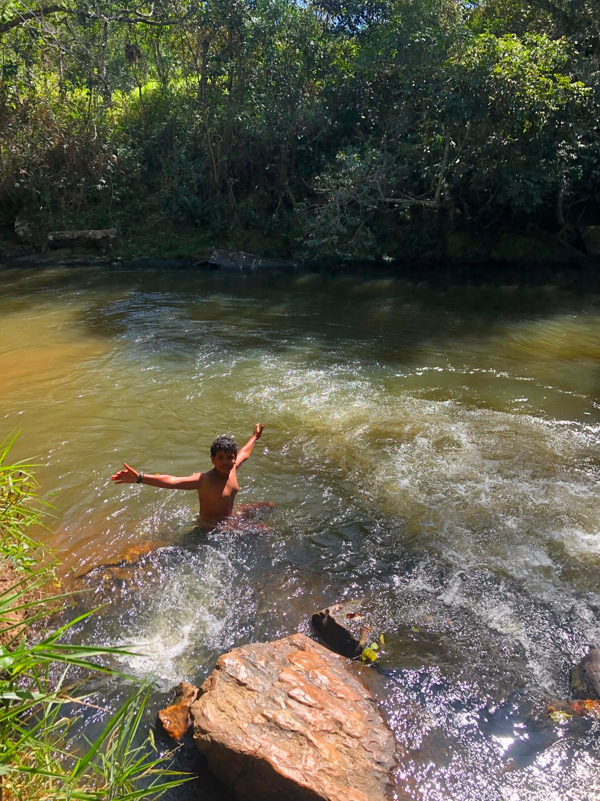 Criança feliz na corredeira do rio