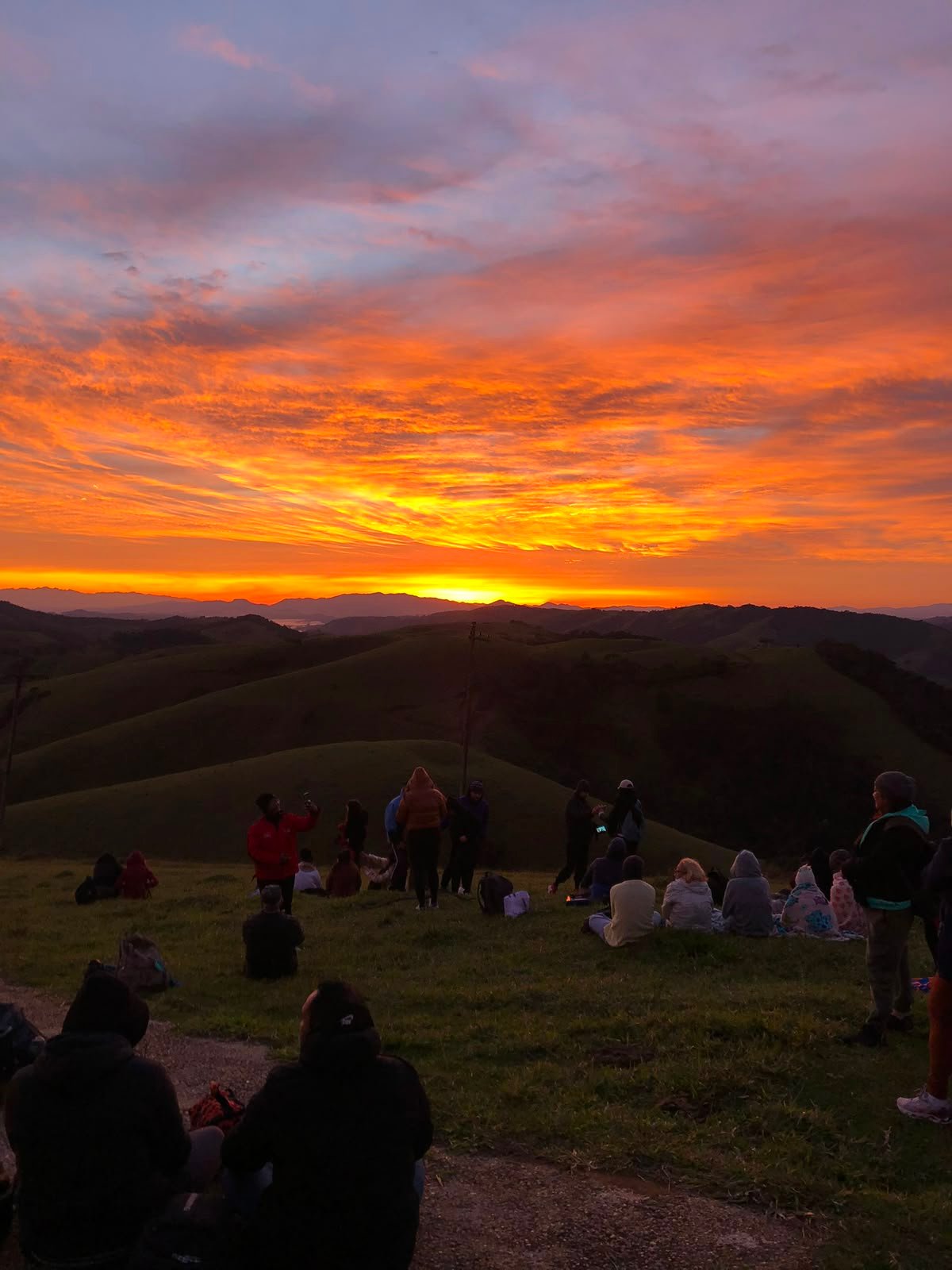 Pôr do sol laranja intenso com grupo no mirante