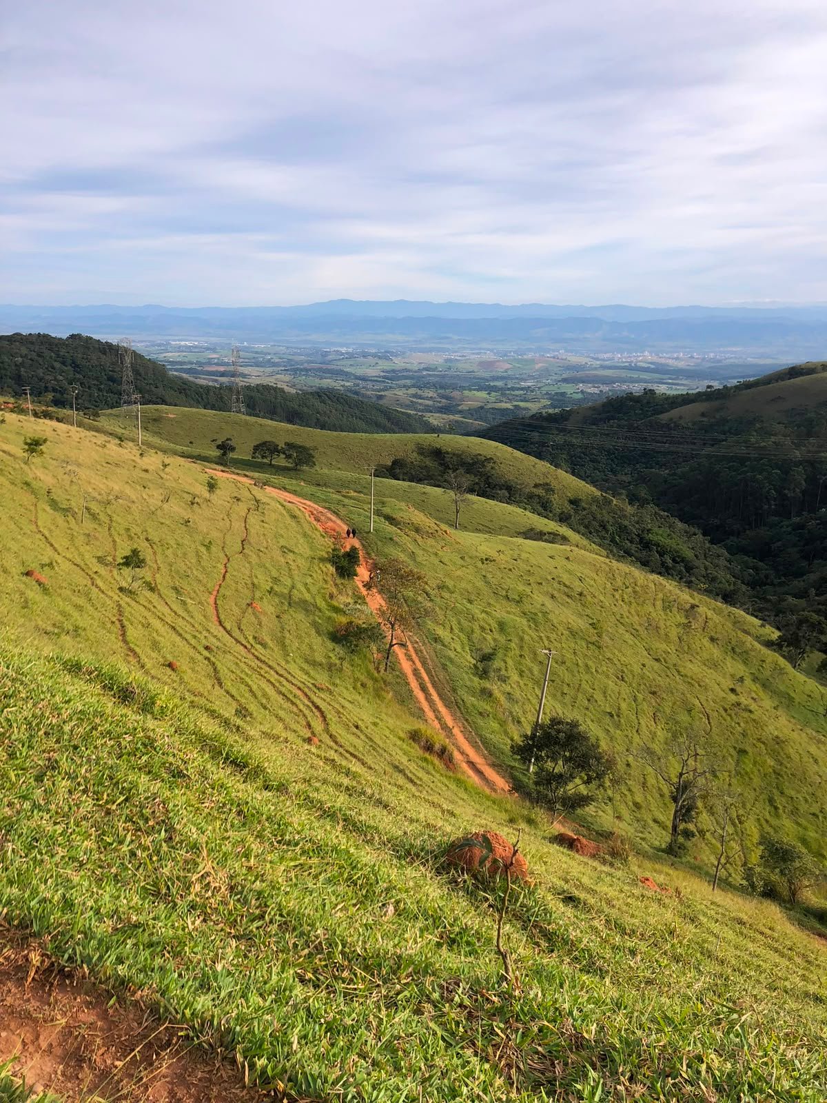 Trilha de terra vermelha na montanha com vista para o vale
