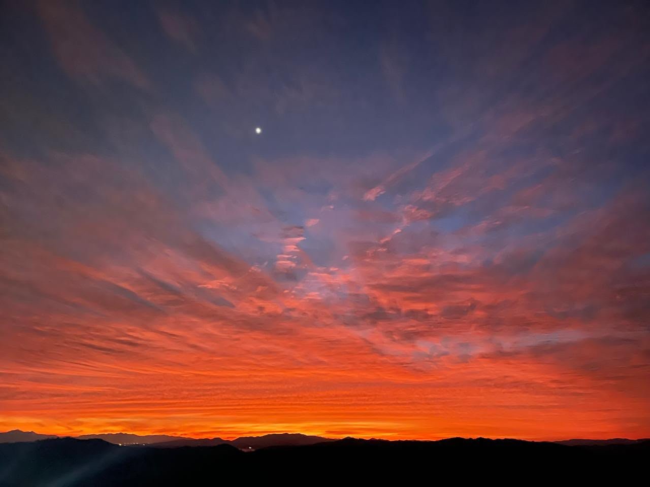Grupo assistindo o pôr do sol laranja sobre as montanhas